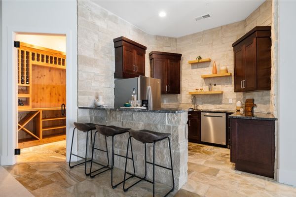 Basement kitchen with bar and barstools and wine cellar behind